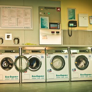 Das Bild zeigt eine Reihe von Waschmaschinen in einem Waschsalon.