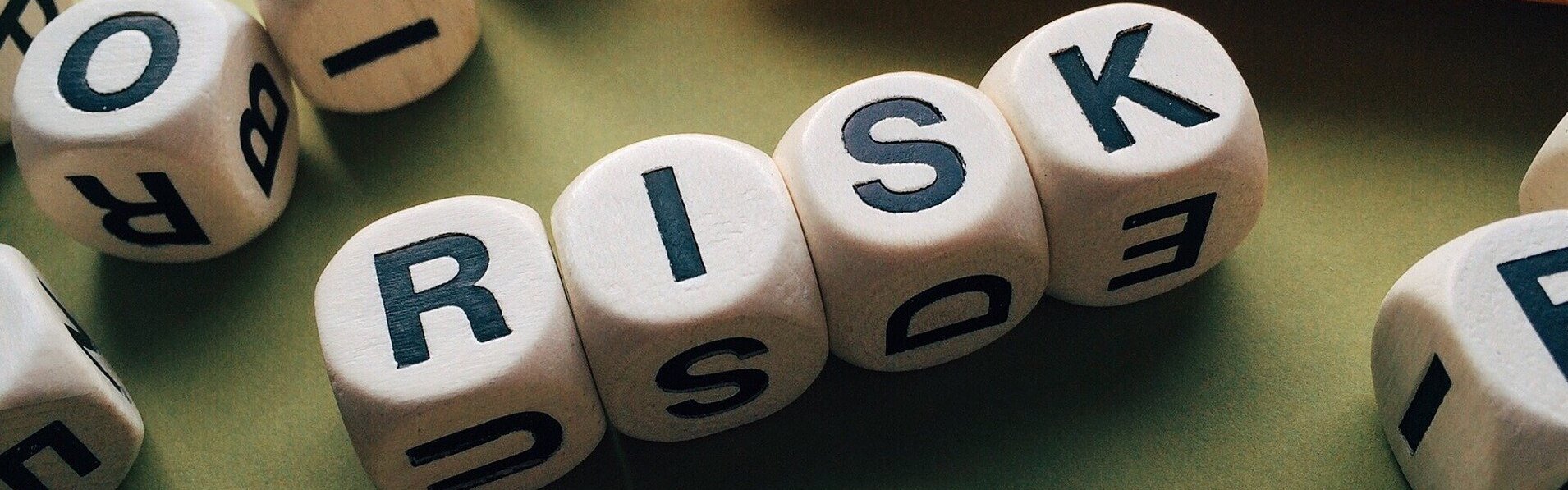 Das Bild zeigt Würfel mit Buchstaben darauf, die das englische Wort "Risk" ergeben.