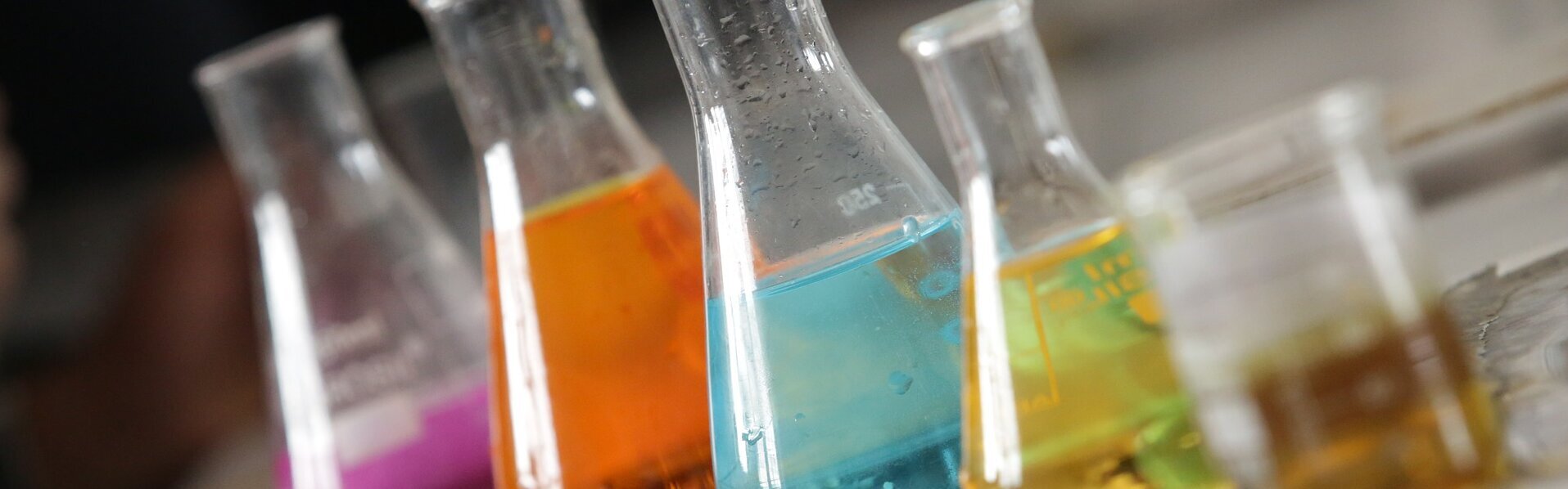 Das Bild zeigt verschiedene Gefäße mit Chemikalien in einem Labor.